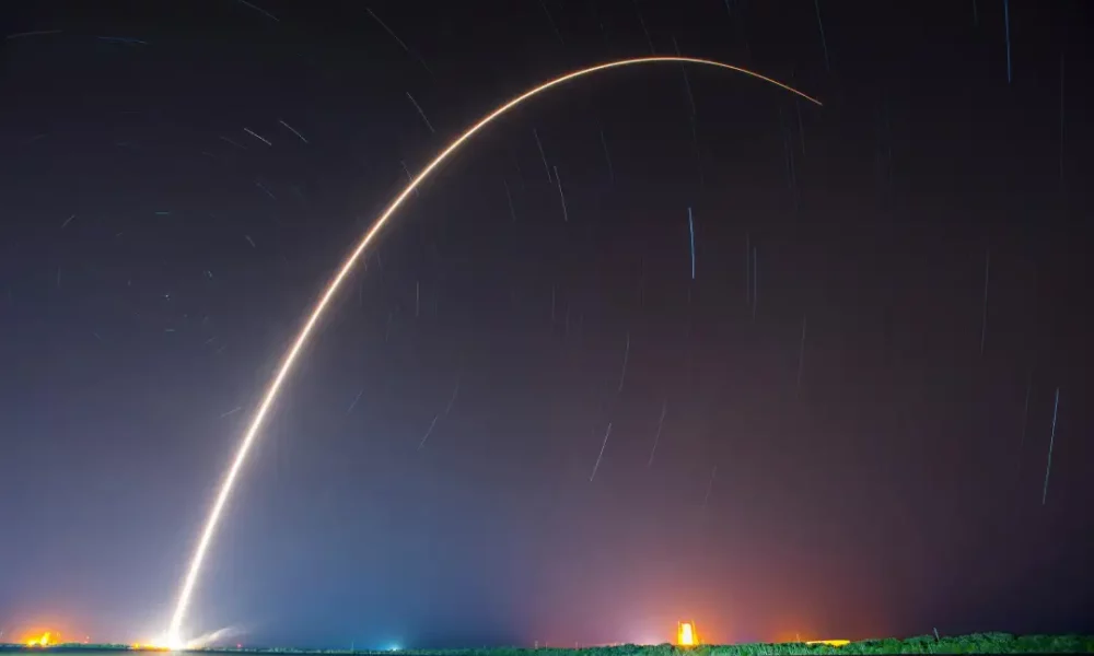 A time-lapse photograph of a Space X rocket launch on a starry night.