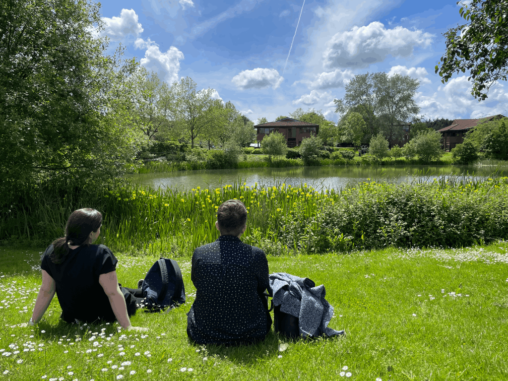 Two women relax by the upper lake at Surrey Research Park