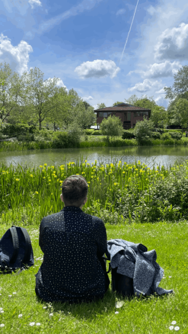 Two women relax by the upper lake at Surrey Research Park