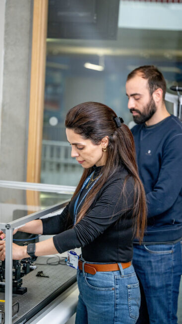 A man and a woman work side-by-side on a piece of scientific equipment