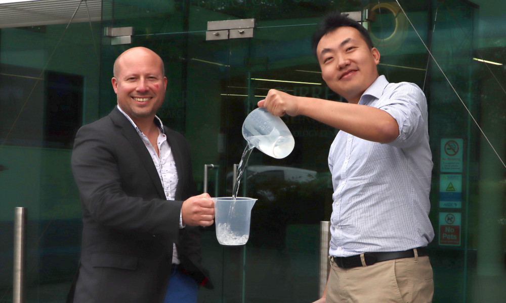 Two men with jugs. The man on the right pours liquid into the jug of the man on the left